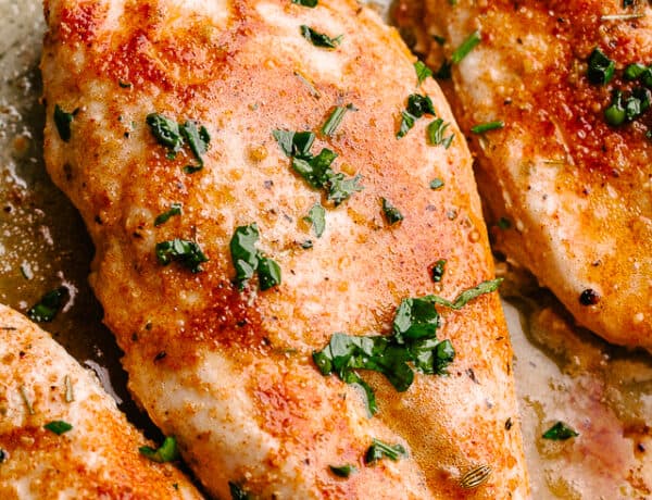 Photo of oven baked chicken breasts garnished with parsley.