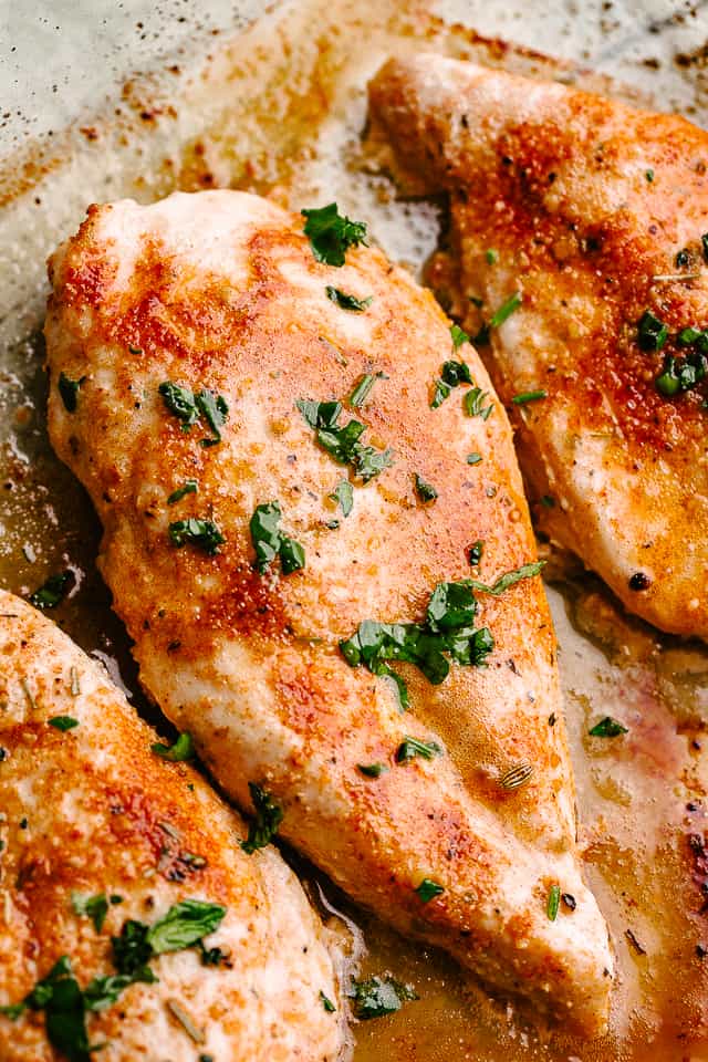 Baked, seasoned chicken breast on a baking sheet.