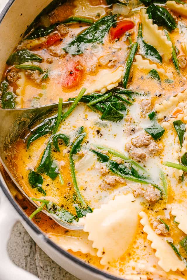 Close up image of a soup with spinach and ravioli.