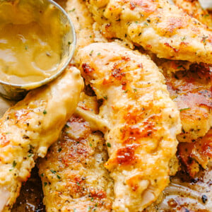 A close-up photo of chicken tenders and a small serving bowl filled with mustard sauce.