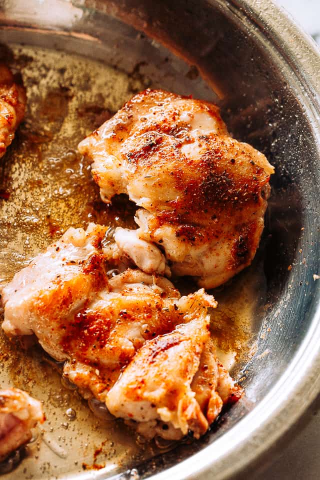 Boneless chicken thighs searing in a pot.
