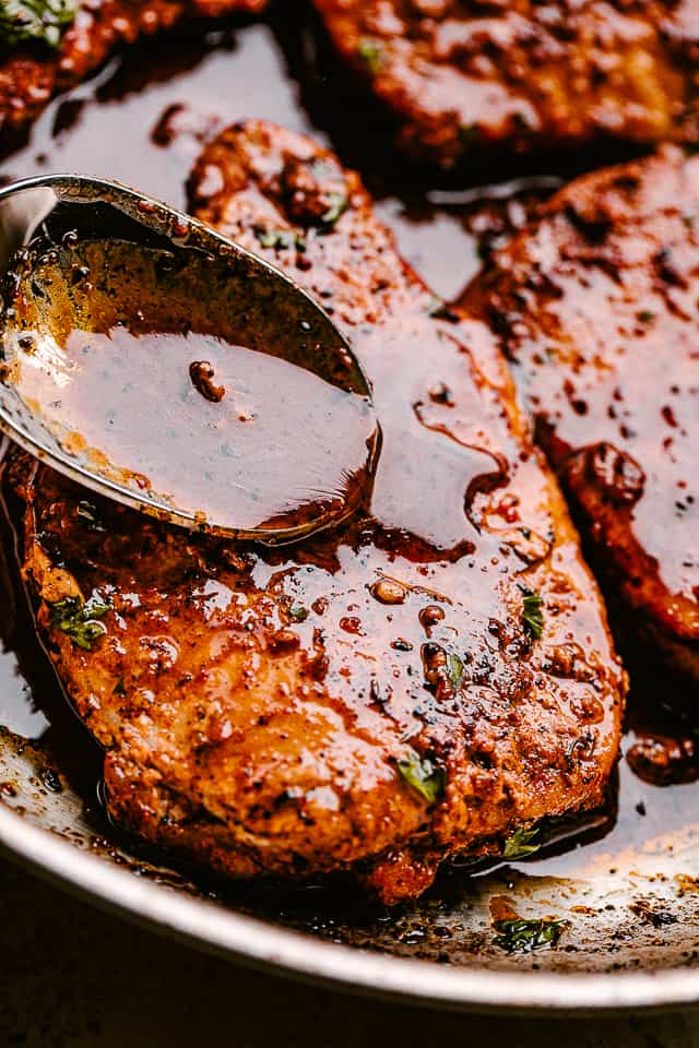 Spooning sauce over pan fried pork chops