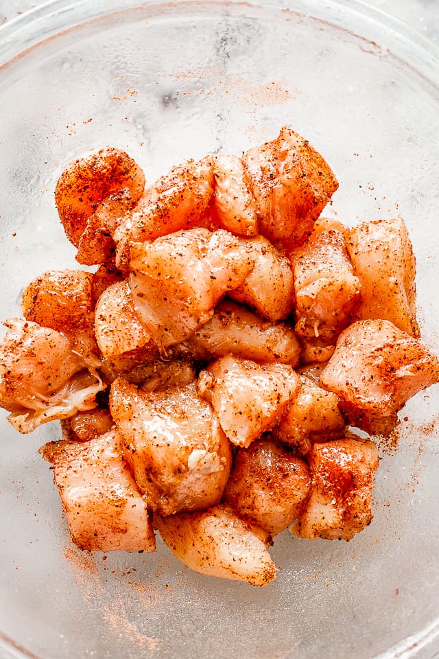Bowl of chicken breasts cut into chunks, and sprinkled with seasoning.