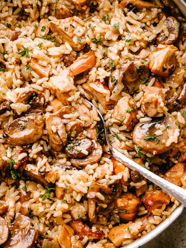 Chicken and mushrooms sauteing in a pan with rice