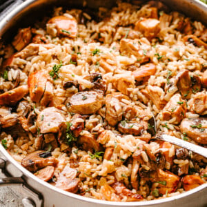 Chicken, mushrooms, and rice in a pan being stirred