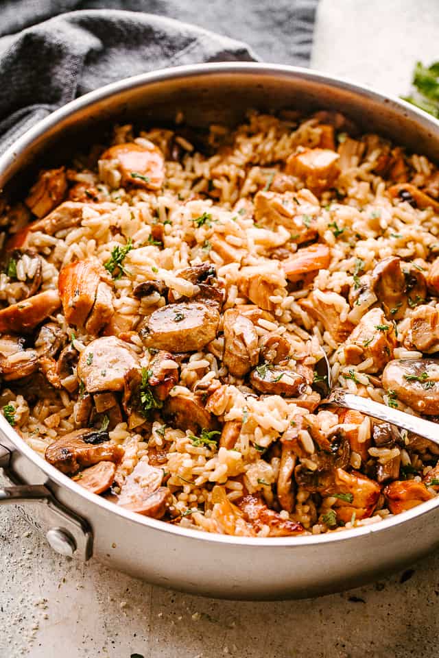Chicken, mushrooms, and rice in a pan being stirred