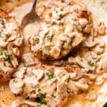 Creamy mushrooms spooned over chicken in a skillet garnished with parsley