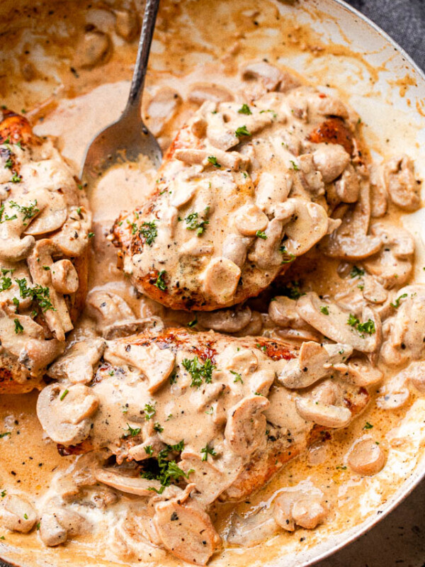 Creamy mushrooms spooned over chicken in a skillet garnished with parsley