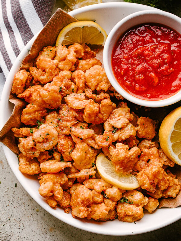 Popcorn shrimp on a plate with lemon and dipping sauce