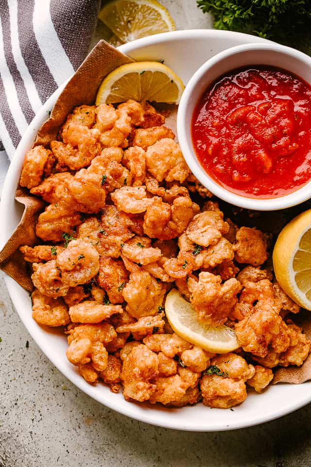 Popcorn shrimp on a plate with lemon and dipping sauce