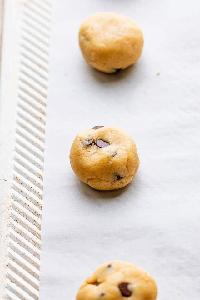 Chilled cookie dough rolled into balls and placed on a parchment lined baking sheet. 