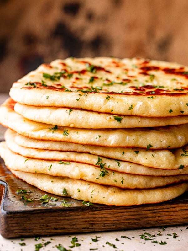 Stack of homemade flatbread on a wooden board.