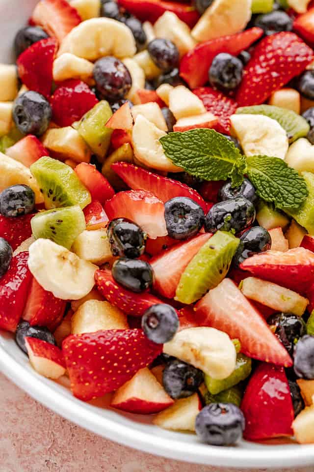 Fresh fruit salad in a bowl garnished with fresh mint leaves. 