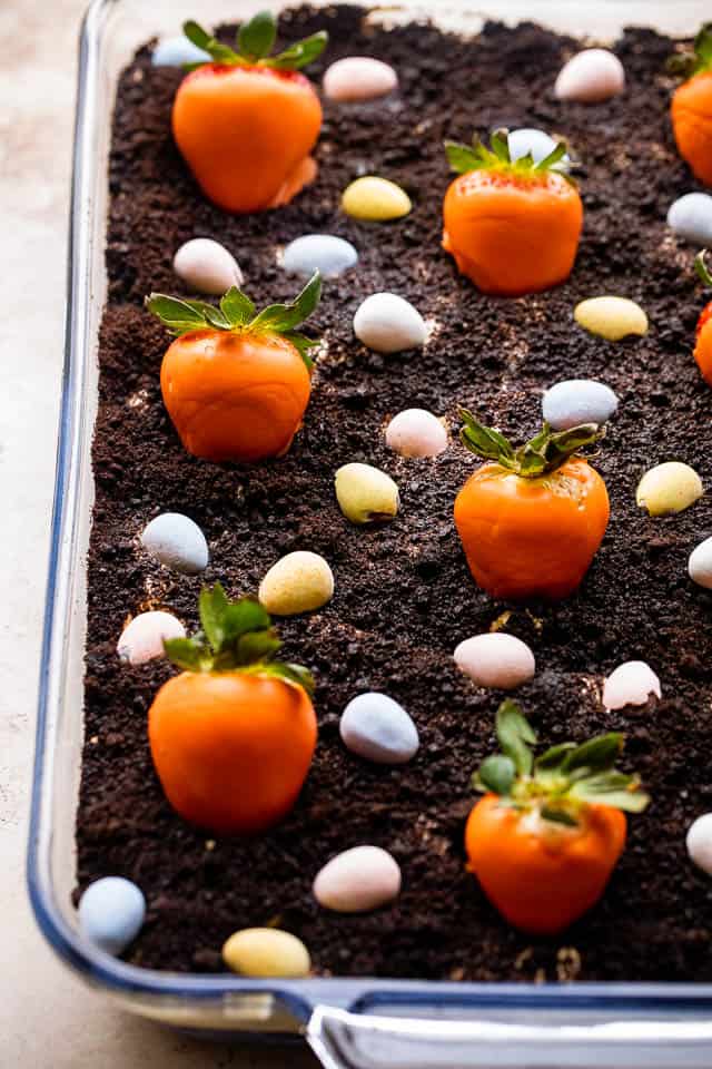 Oreo Dirt Cake topped with chocolate covered strawberries and chocolate egg candy