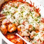 white baking dish filled with baked meatballs covered in marinara sauce and melted cheese