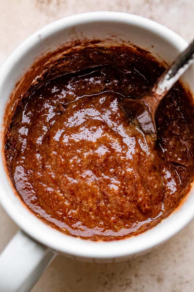 Stirring through a chocolate batter inside a mug.