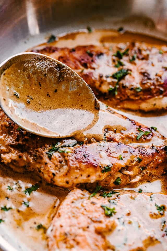 spooning creamy balsamic sauce over chicken breasts