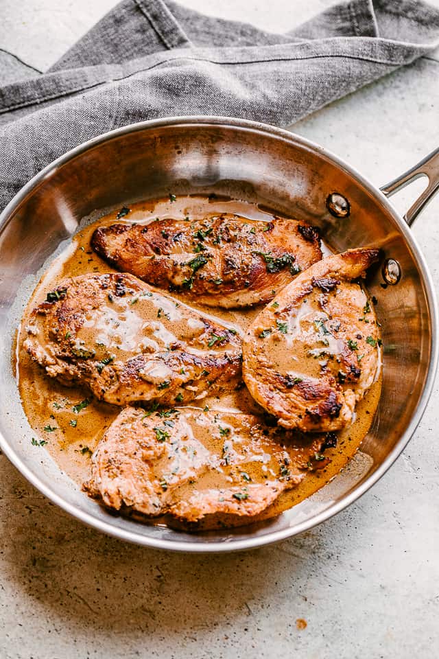 top view of four chicken breasts in a skillet with creamy balsamic sauce