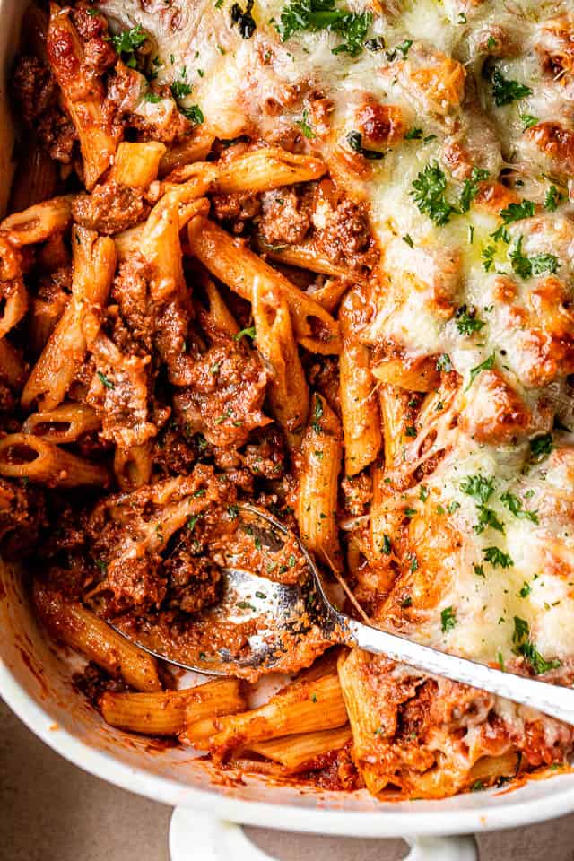 penne pasta casserole with ground beef in a white baking dish