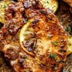 close up top view shot of baked pork chops topped with a slice of lemon