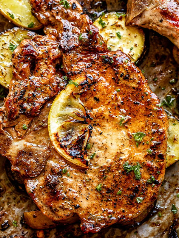 close up top view shot of baked pork chops topped with a slice of lemon