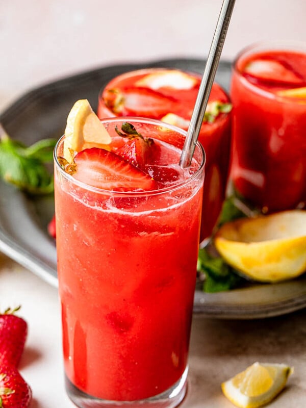 strawberry lemonade sangria in a tall glass and topped with strawberries and lemons