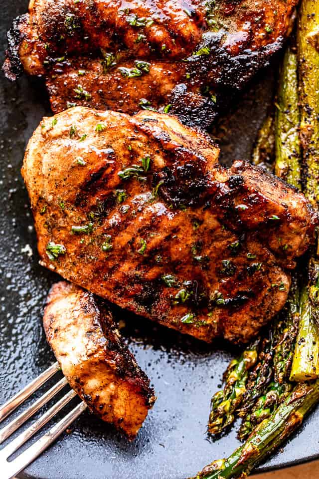 grilled pork chops served on a black plate with asparagus