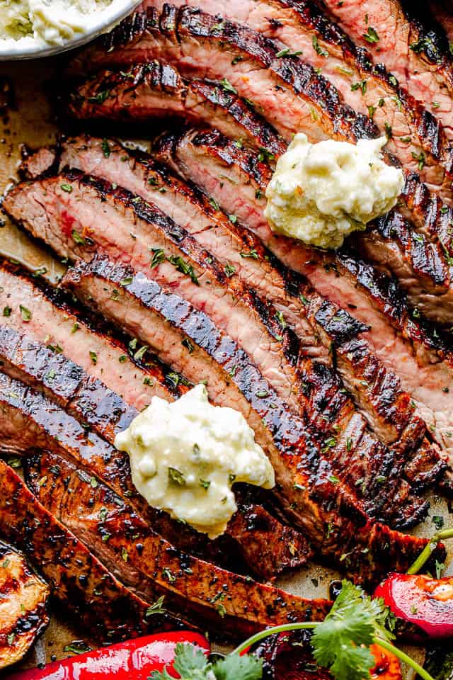 top shot of flank steak slices topped with dollops of bleu cheese butter