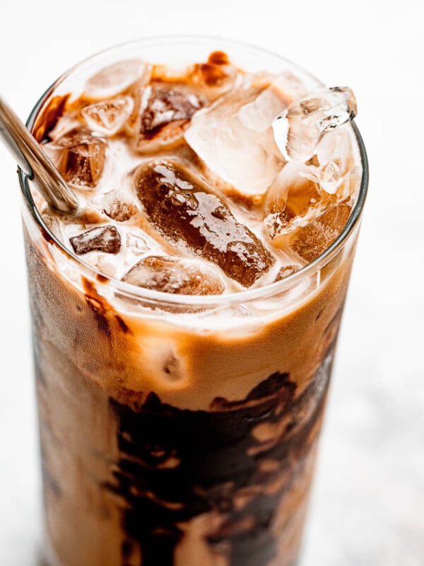 ice floating on top of coffee in a drinking glass