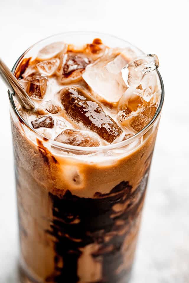 ice floating on top of coffee in a drinking glass