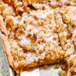 top shot of a spatula removing apple pie from a sheet pan.