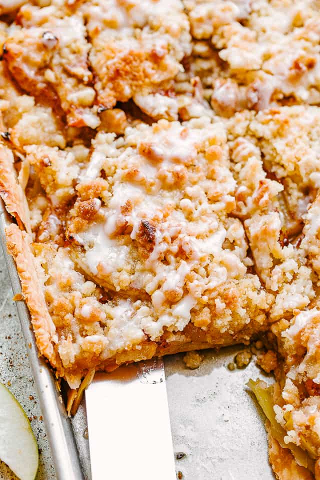 top shot of a spatula removing apple pie from a sheet pan.