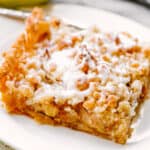 slice of apple slab pie on a white dessert plate set next to a green apple.