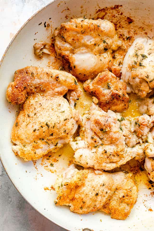 overhead shot of boneless skinless chicken thighs in a white skillet