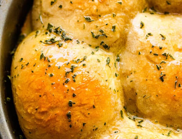 overhead close up shot of baked dinner rolls sprinkled with herbs and set in a pan