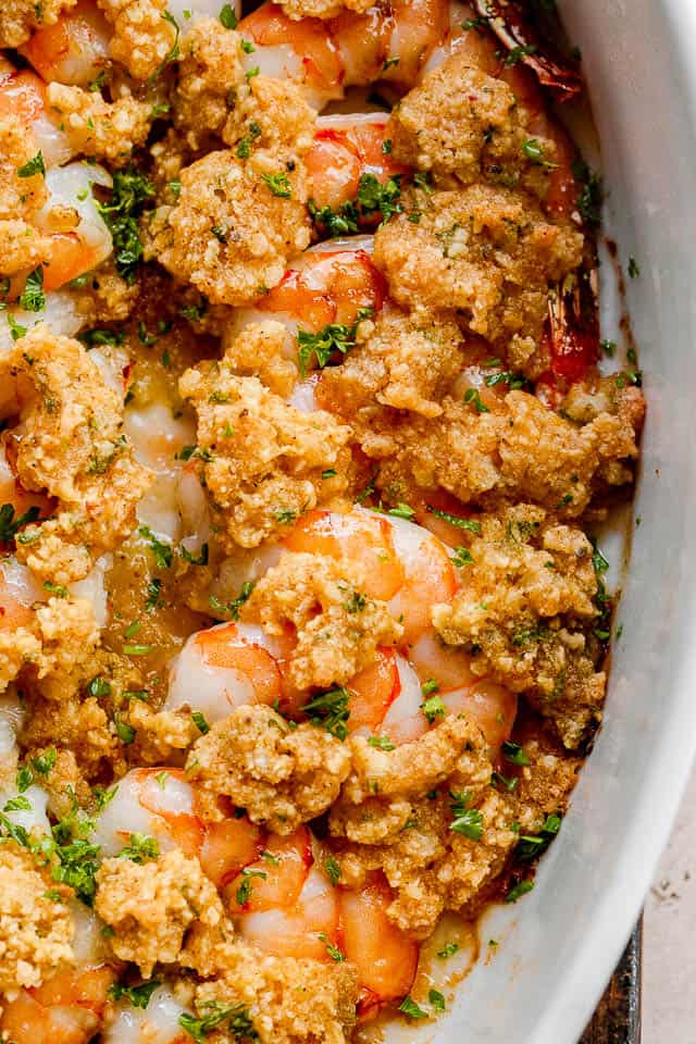 close up shot of garlic butter baked shrimp in a white dish