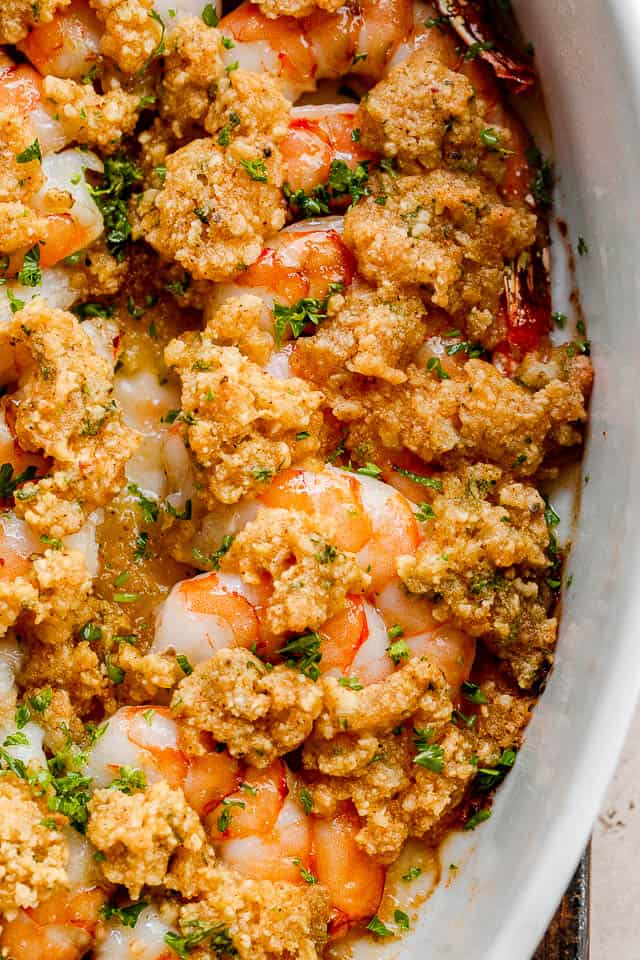 close up shot of garlic butter baked shrimp in a white dish.