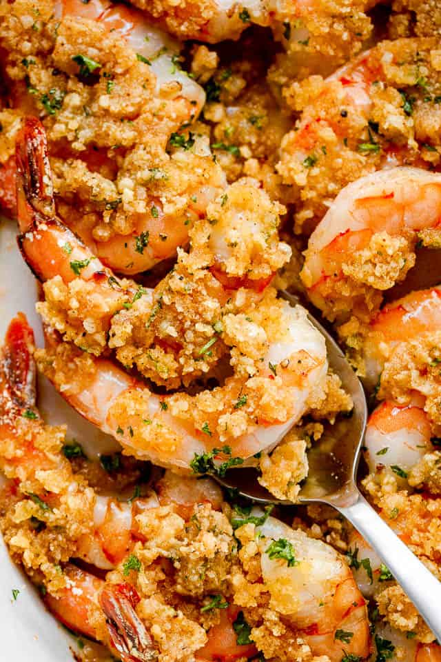 scooping out Garlic Butter Baked Shrimp with silver spoon