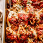 close up top view of pasta shells stuffed with beef and topped with shredded cheese and marinara