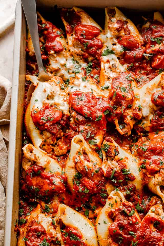 close up top view of pasta shells stuffed with beef and topped with shredded cheese and marinara