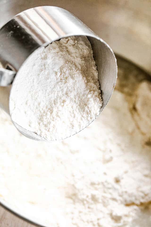 side shot of a silver measuring cup filled with flour