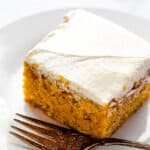 side shot of frosted pumpkin bar on a plate with a fork next to it