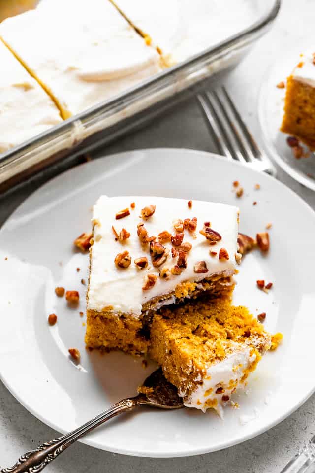 top shot of pumpkin bar slice topped with cream cheese frosting a chopped pecans