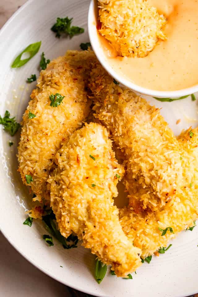 overheat shot of chicken tenders on a white plate served with dipping sauce
