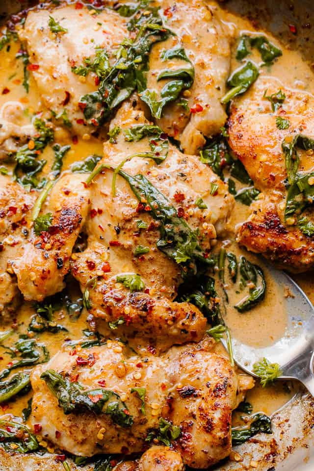 overhead close up shot of boneless skinless chicken thighs in a creamy sauce with spinach