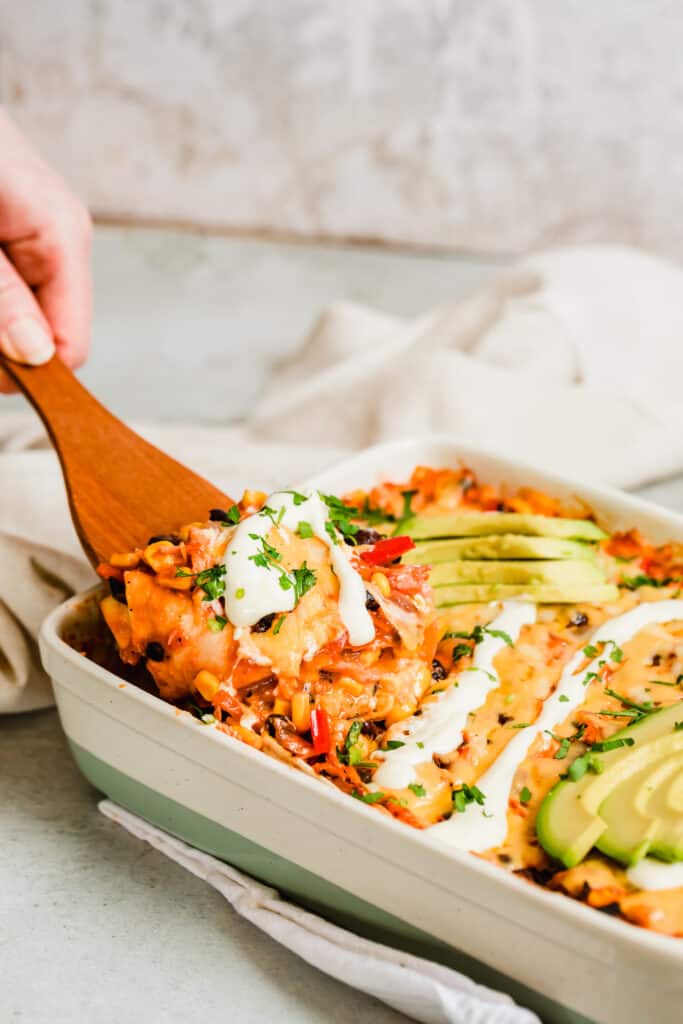 Digging into a Chicken Enchilada Casserole with a Wooden Spoon