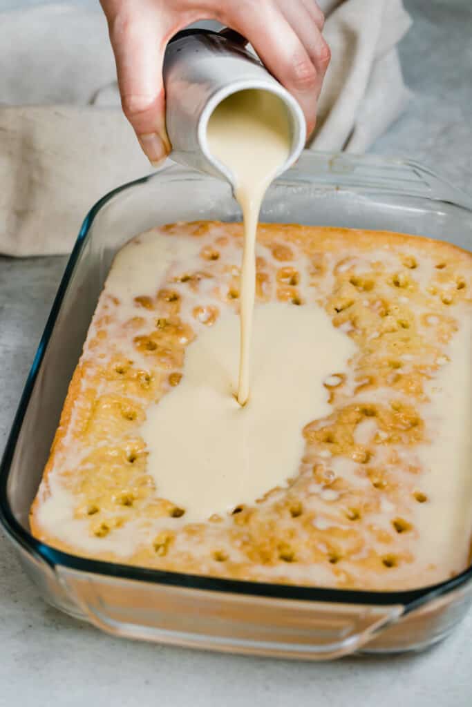 The Milk Mixture Being Poured Over a Pan of Tres Leches Cake