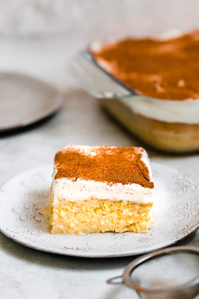 A Slice of Tres Leches Cake Next to the Rest of the Cake in a Pan