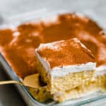 A Square of Tres Leches Cake Being Lifted From the Glass Pan with a Serving Spatula