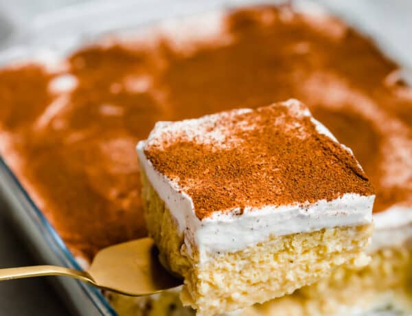 A Square of Tres Leches Cake Being Lifted From the Glass Pan with a Serving Spatula